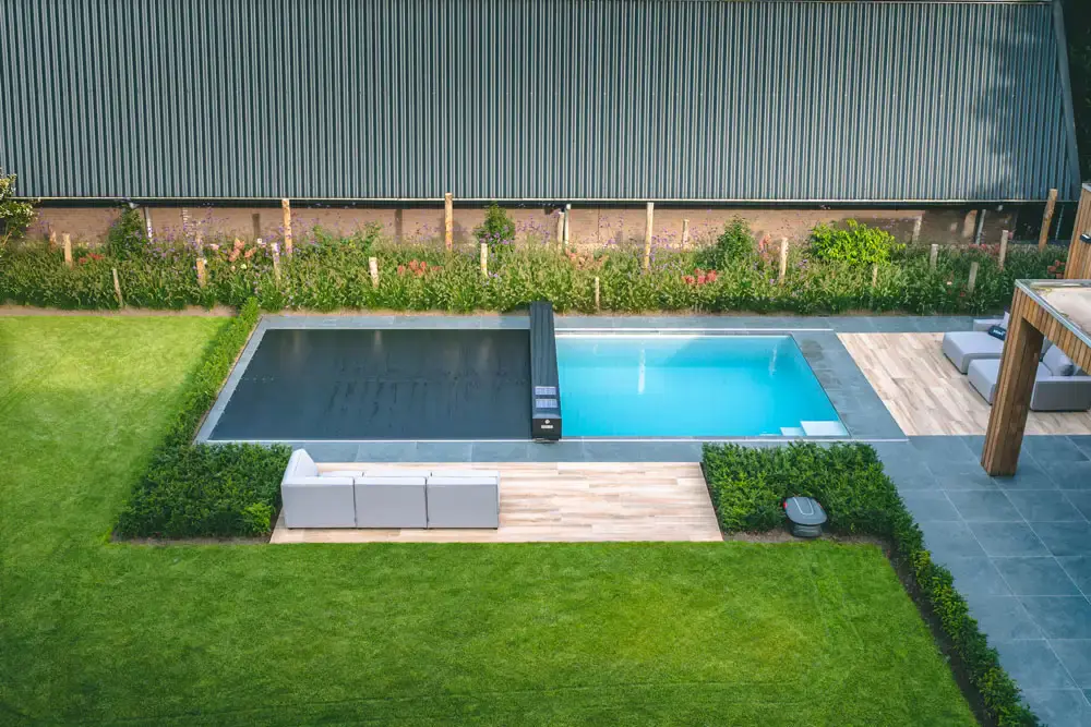 a pool with a black cover and a wooden deck and a fence